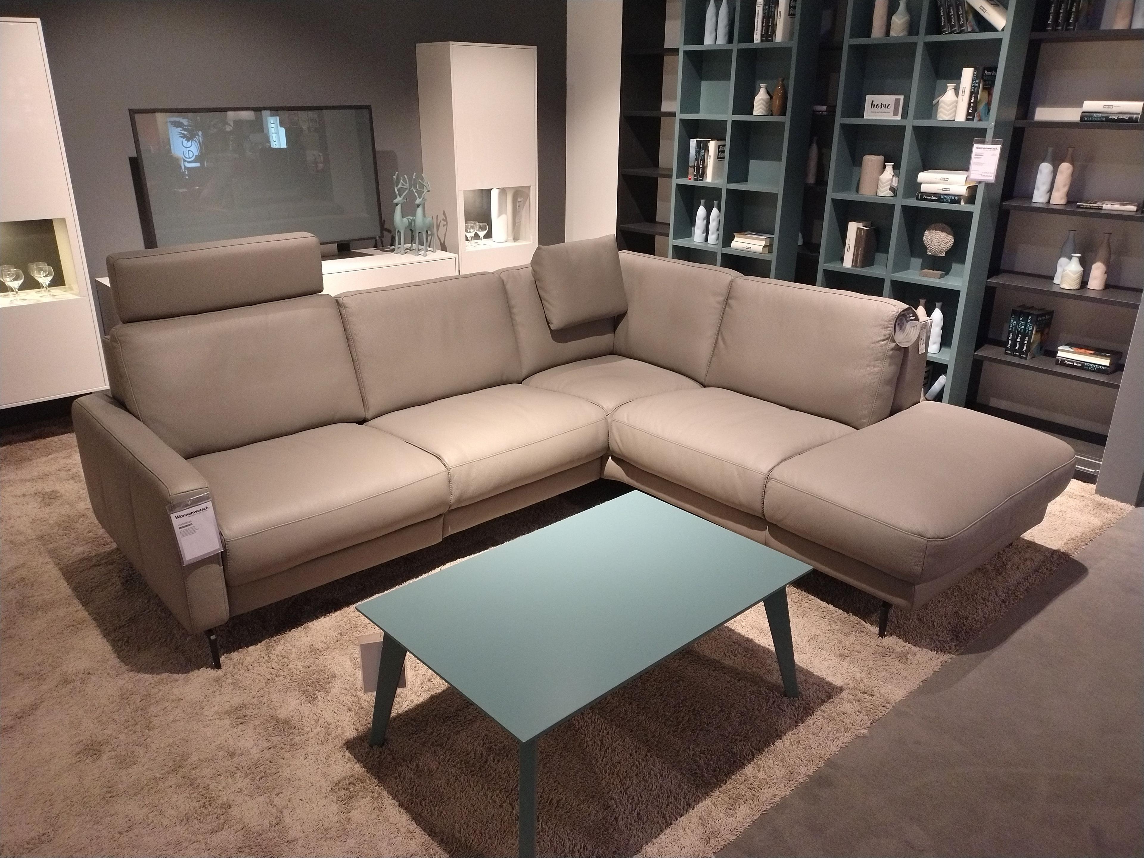 Sofa in Leder mit Armlehne links und offenem Abschluss rechts, im Sitz links eine aufgesteckte Kopfstütze, rechts in der Ecke ein Nackenkissen